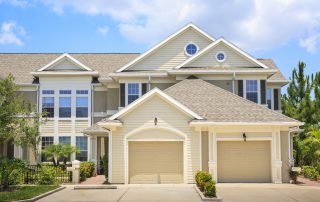 Cream-painted two-story residential exterior with white trim, tan garage doors, and gray shingled roof in Winchester, WV.