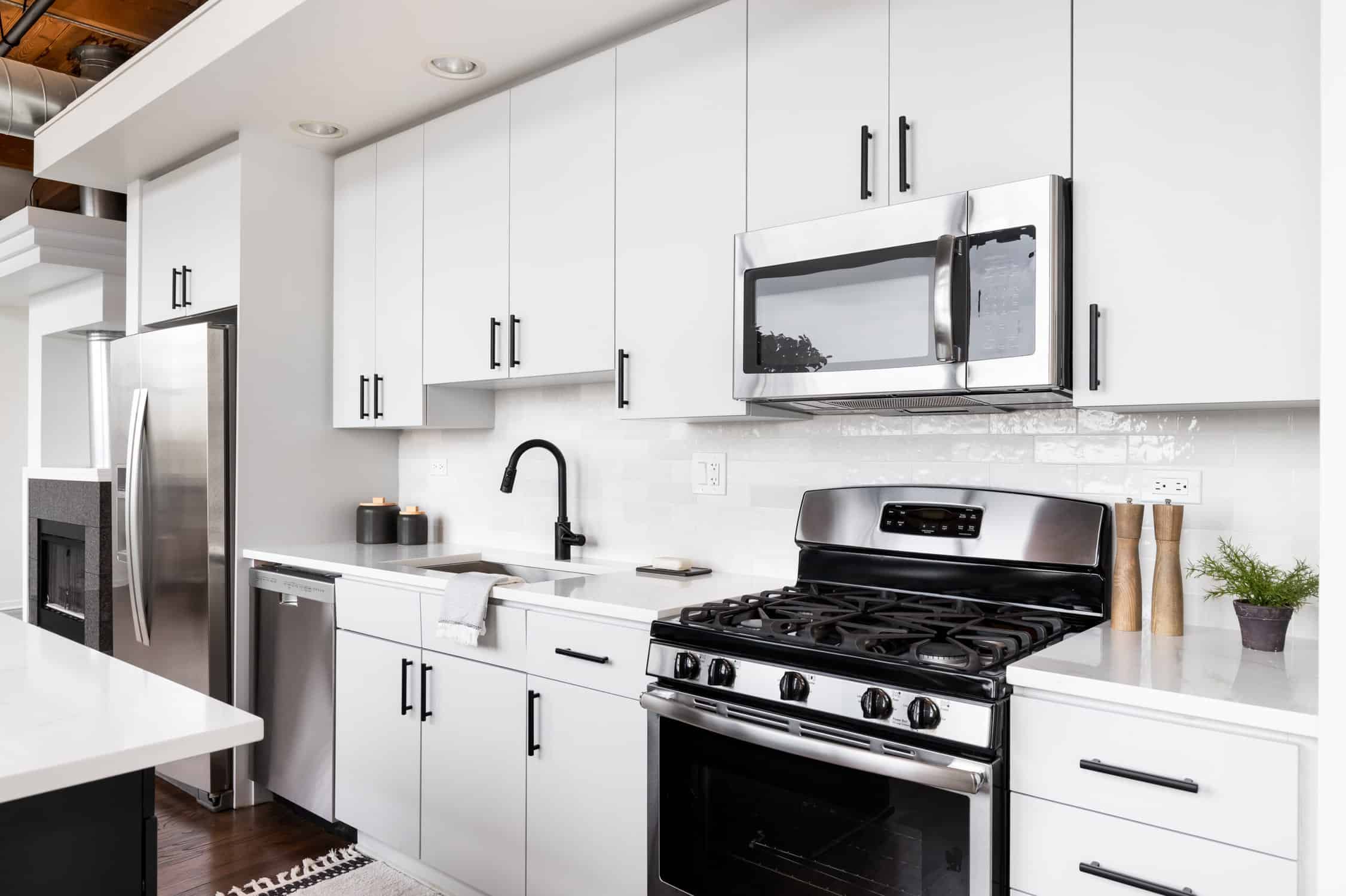 A white kitchen with stainless steel appliances. Cabinet painting