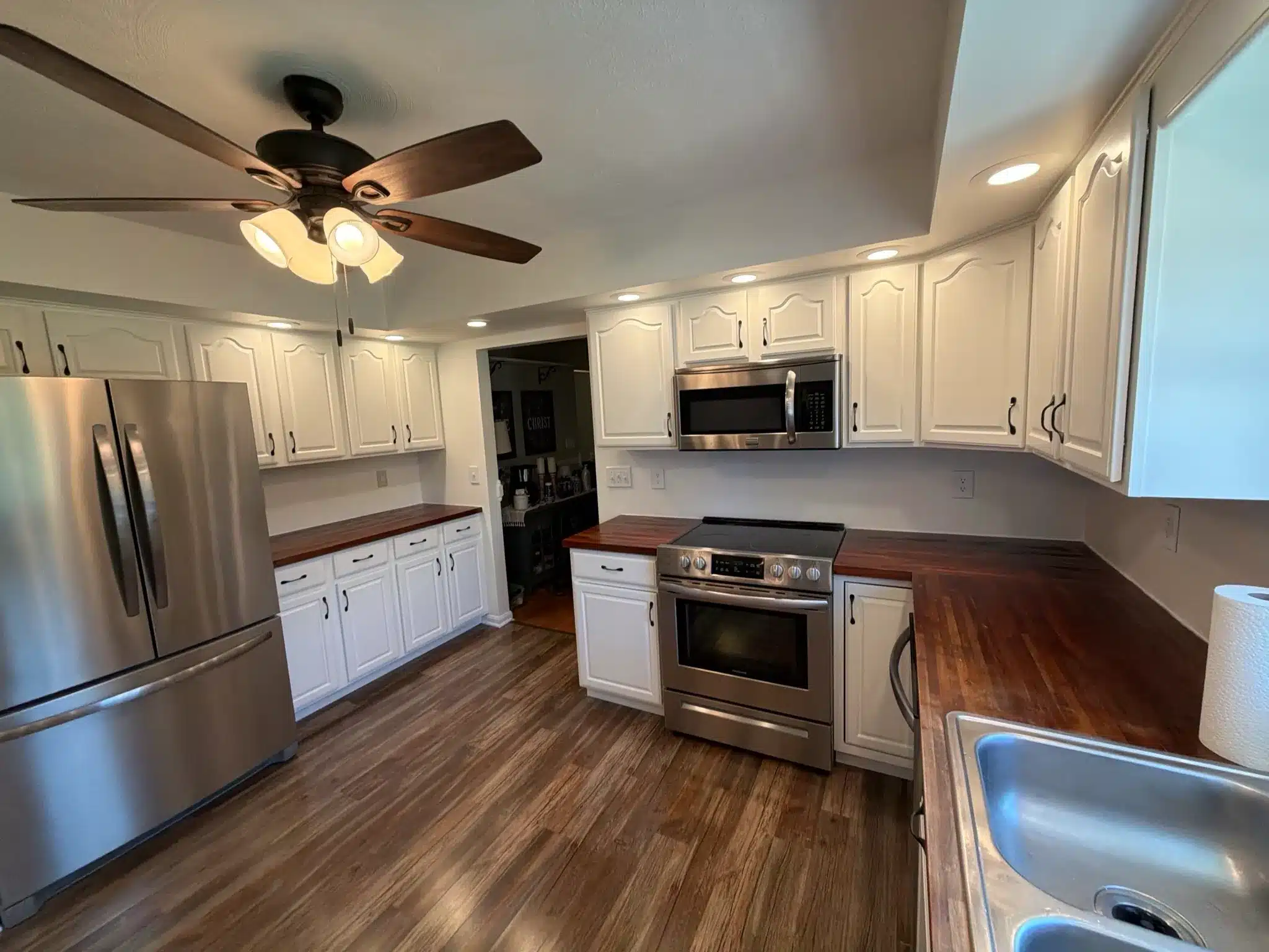 White Painted Kitchen Cabinets White-painted residential kitchen cabinets with wood countertops, stainless steel appliances, and dark wood flooring.